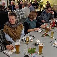 Geselliges Beisammensein an einem festlich gedeckten Tisch, umgeben von Menschen bei einem Weihnachtsessen.
