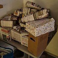 Hochgestapelte, eingepackte Geschenke in Zeitungspapier und dekorativem Papier auf einem Tisch.