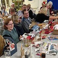 Tisch mit verschiedenen Getränken, Geschenken und Deko, umgeben von feiernden Menschen in einem festlichen Ambiente.