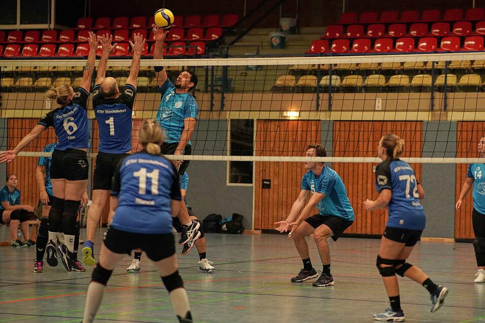 Volleyballspiel: Zwei Spieler springen zum Blocken, während die anderen bereit stehen, um den Ball zu empfangen.