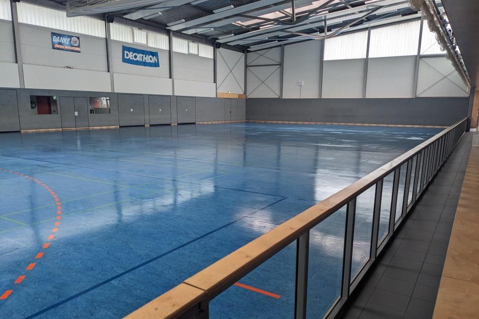 Weite Innenansicht einer Sporthalle mit blauer Kunststofffl&auml;che und klaren Linien f&uuml;r verschiedene Sportarten.